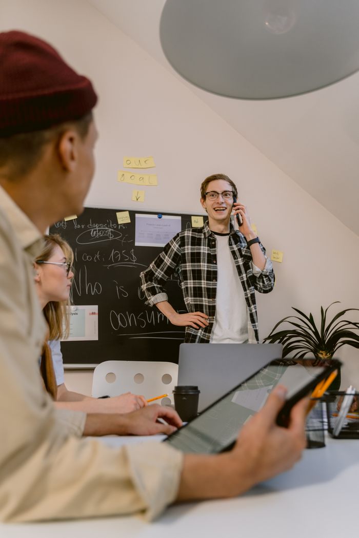 A group of young colleagues engage in a creative office meeting with a focus on digital collaboration.